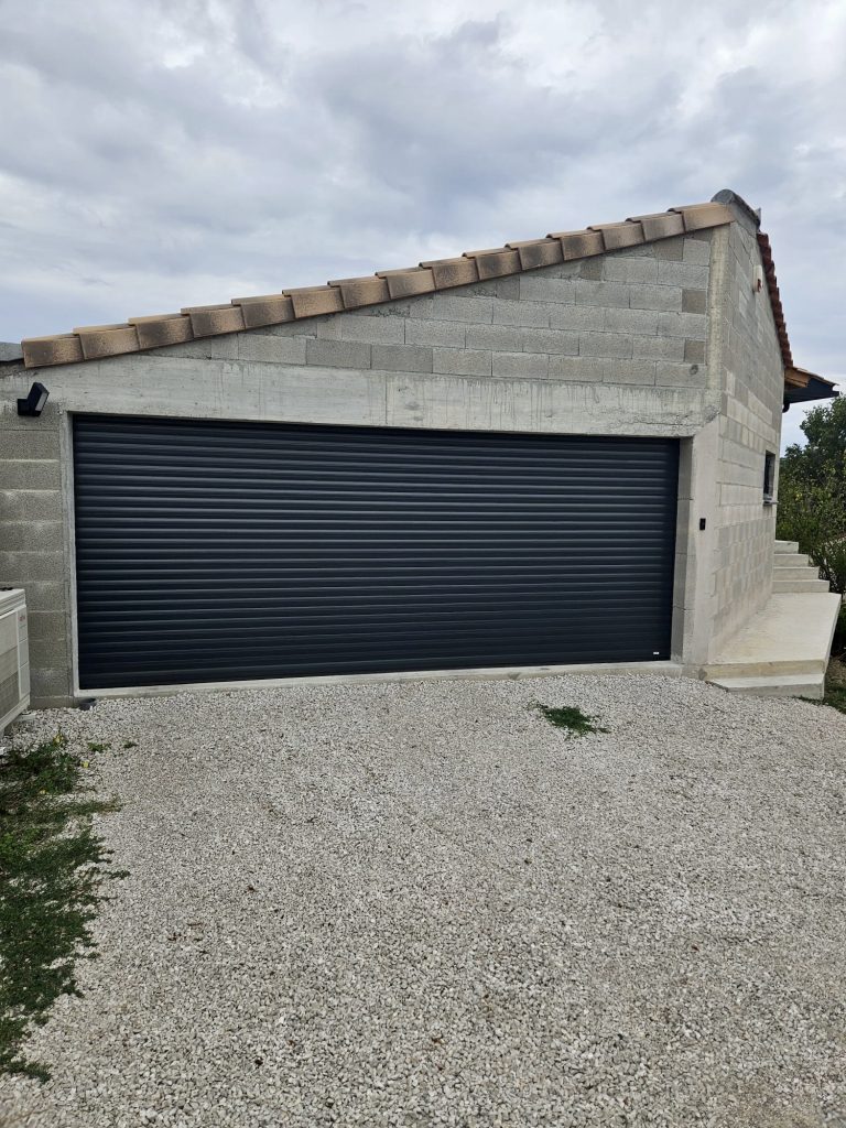Garage moderne avec porte enroulable noire et structure béton