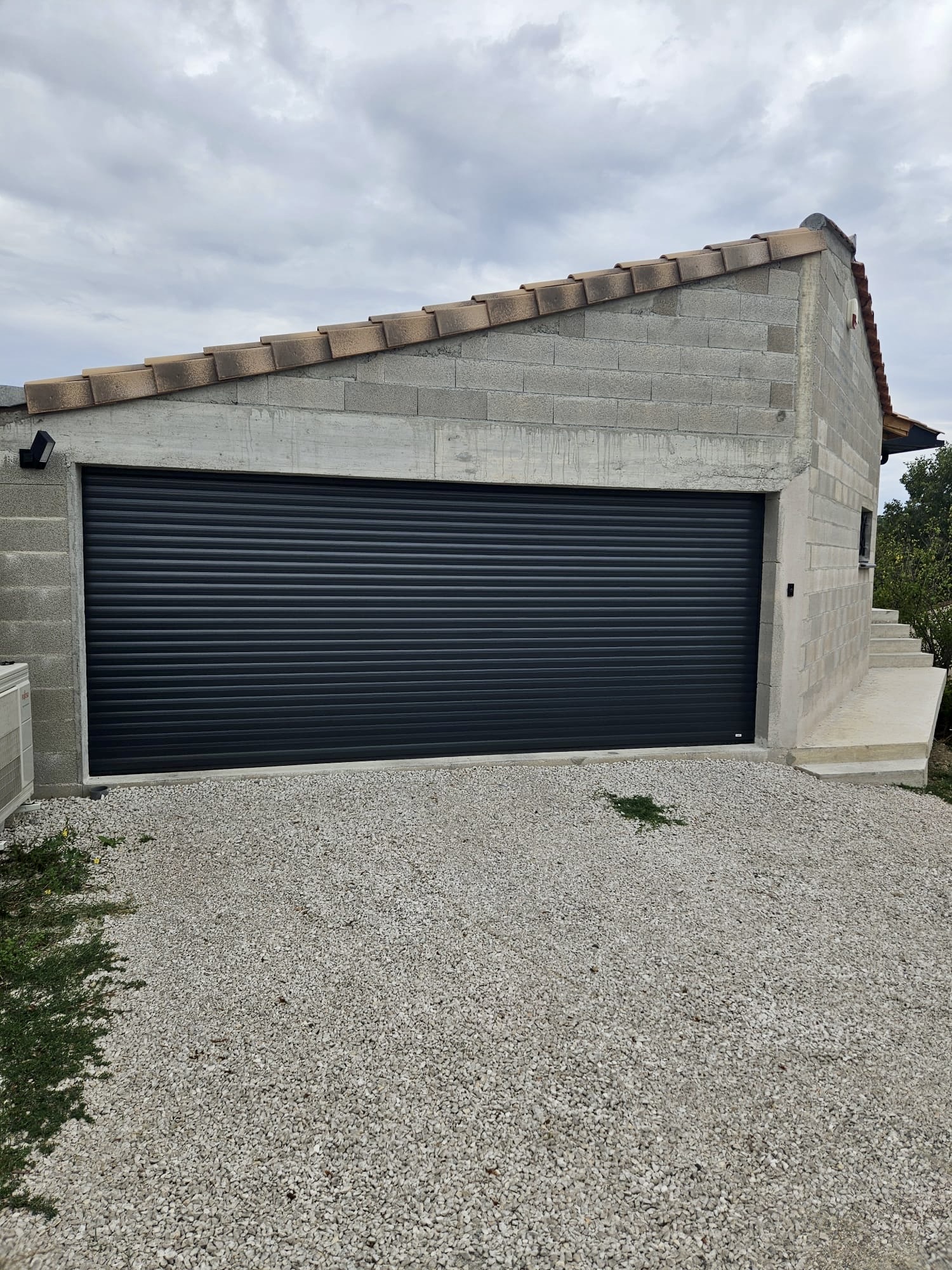 Garage moderne avec porte enroulable noire et structure béton