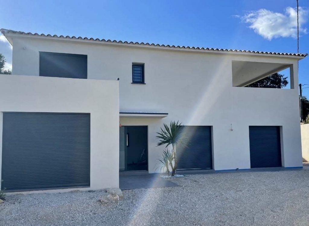 Maison contemporaine blanche avec volets bleus et garage