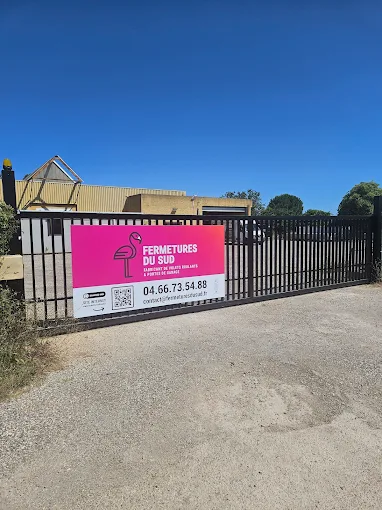 Portail métallique avec panneau publicitaire rose agence immobilière