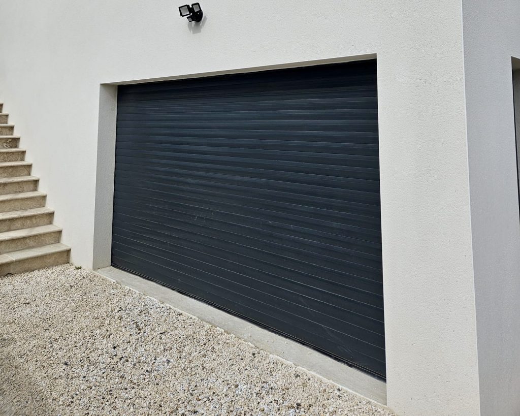 Porte de garage sectionnelle noire sur façade blanche moderne