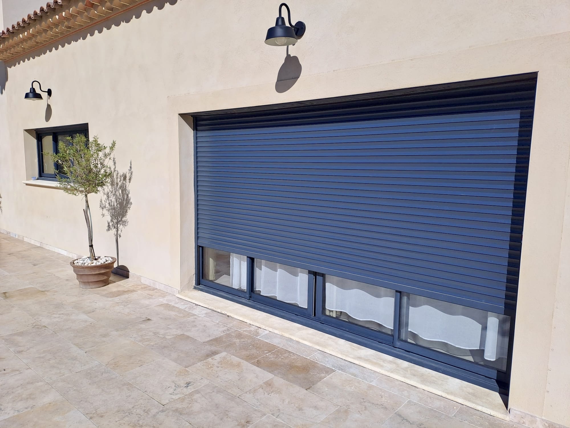 Porte de garage sectionnelle bleu marine avec fenêtres intégrées, façade moderne