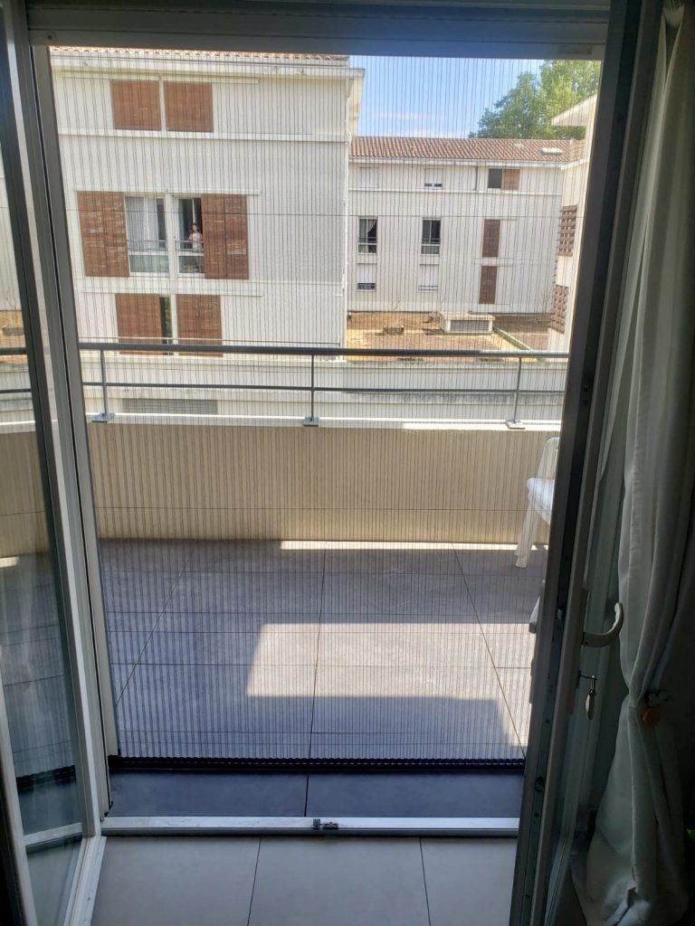 Balcon avec baie vitrée donnant sur immeubles résidentiels modernes