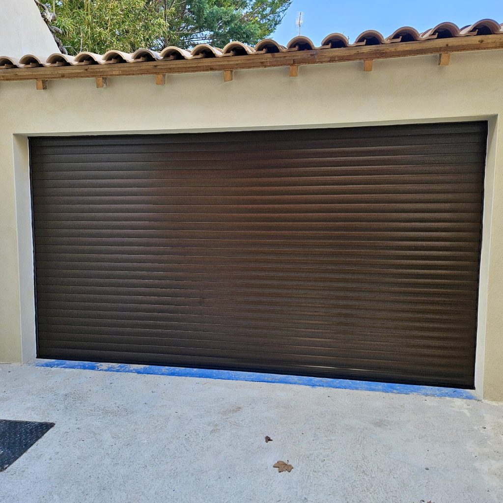 Porte de garage automatique marron bois sur façade maison méditerranéenne